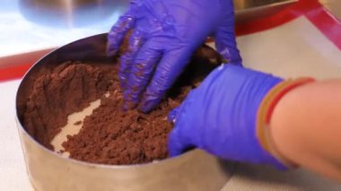 Close-up - hands in rubber gloves. Cooking brownies, chocolate cake. Chef's hands are kneading chocolate dough.