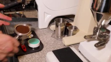 Master class barista. Freshly ground coffee for the coffee machine. The process of making real espresso. Professional coffee machine in a coffee shop. Barista's hands close-up.