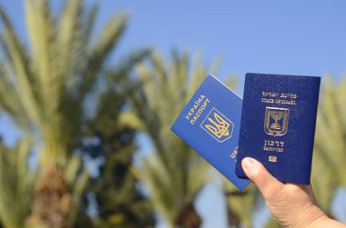 The concept of changing citizenship. Repatriation. Law of Return. Women's hands holding an Israeli passport and a Ukrainian passport
