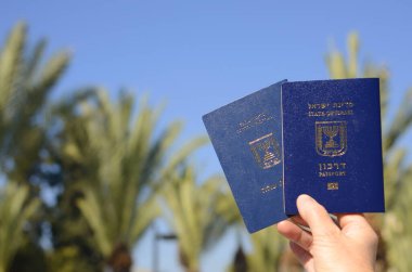 Israeli passport Darkon and Certificate of new immigrant. . A woman's hand is holding two Israeli biometric passports. Concept: travel, citizenship, emigration. Translation: Darkon, Teudat ole
