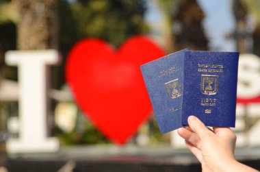 Israeli passport Darkon and Certificate of new immigrant. . A woman's hand is holding two Israeli biometric passports. Concept: travel, citizenship, emigration. Translation: Darkon, Teudat ole