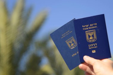 Israeli passport Darkon and Certificate of new immigrant. . A woman's hand is holding two Israeli biometric passports. Concept: travel, citizenship, emigration. Translation: Darkon, Teudat ole