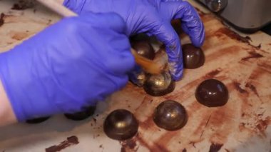 Close-up - female hands in rubber gloves. Cooking chocolate candies, handmade. Craft factory - making sweets.