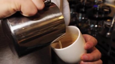 Barista work. The process of making latte and cappuccino. Close-up male hands pour milk in a circular motion into a cup.