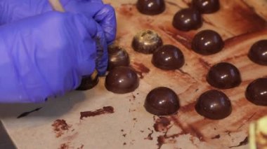 Close-up - female hands in rubber gloves. Cooking chocolate candies, handmade. Craft factory - making sweets.