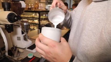 Barista work. The process of making latte and cappuccino. Close-up male hands pour milk in a circular motion into a cup.