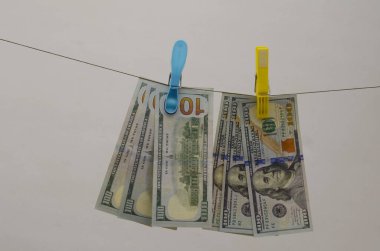 Yüz dolarlık banknotlar bir ipe asılı. Mandal parası. Kavram: vergiler, yatırımlar, elektrik faturaları, primler, tasarruflar, maaşlar. Dolar nakit