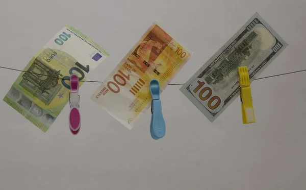 Concept: the Israeli shekel against the dollar and the euro. Cash New Israeli Shekel, American Dollar, Euro. Paper banknotes hang on clothespins. Concept: taxes, exchange rate, investment, savings, profit.
