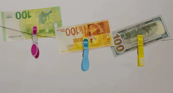 Concept: the Israeli shekel against the dollar and the euro. Cash New Israeli Shekel, American Dollar, Euro. Paper banknotes hang on clothespins. Concept: taxes, exchange rate, investment, savings, profit.