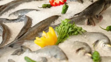 Showcase with fresh fish in a restaurant. Dorado and sea bass in ice, decorated with fruits. Counter with fish, seafood