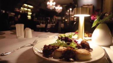 A dish in a restaurant, cheese pancakes and fried artichokes with lettuce. Fresh healthy vegan food. Romantic setting, trendy restaurant