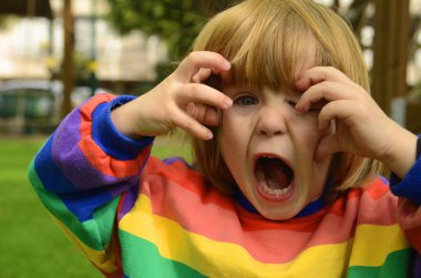 A cute little boy with an open mouth. A positive child screams funny, swears, is outraged, laughs. Close-up portrait. Preschooler emotions