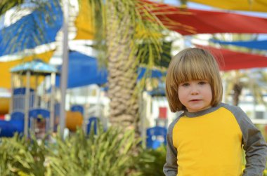 Positive boy 4 years old at the playground. Bright playground, palm trees, good mood. The face of the child, positive emotions