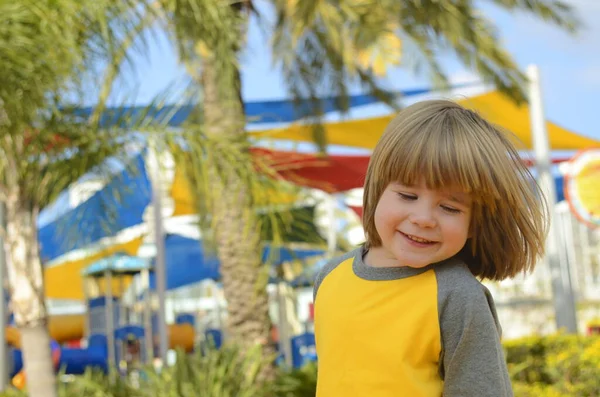 Positive boy 4 years old at the playground. Bright playground, palm trees, good mood. The face of the child, positive emotions