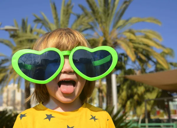 stock image A cute boy in large glasses in the shape of a heart. The child rejoices in the holiday. Concept: Mother's Day, Purim, carnival, going to the circus, entertainment park. Traveling with children a symbol of love and hugs.