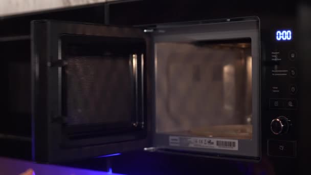 一个男人把食物放进微波炉加热 半成品 微波和男性手部特写 — 图库视频影像