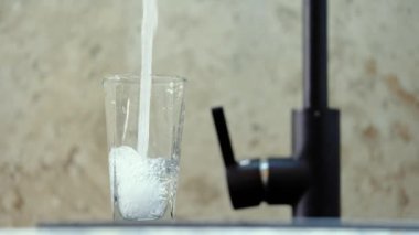 Musluktan temiz içme suyu. Ağır çekim. Bir bardak su, güzel bir çerçeve. Kavram: susuzluk, tasarruf kaynakları, su kullanımı, kamu hizmeti fiyatları, sifonu çekme.