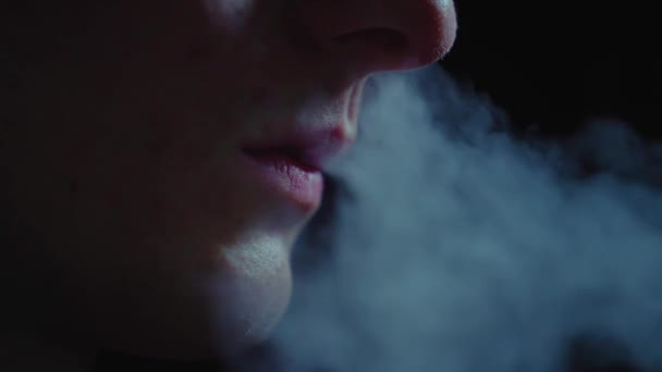 吸烟用的电器 一个男人在黑暗中抽一支电子烟 Cig Vsping 吸烟的害处 慢动作 在黑暗的背景下抽烟 一个没有脸的人手里拿着一支电子香烟 — 图库视频影像