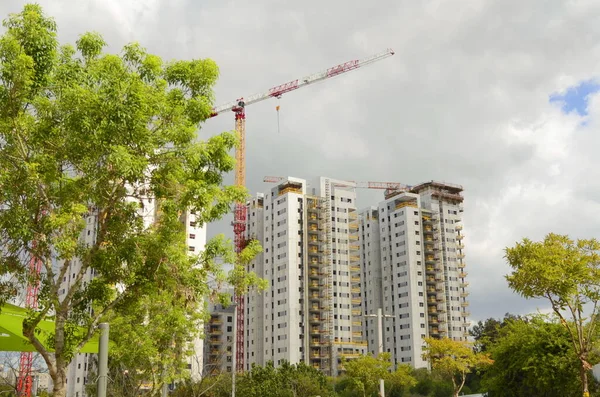 Construction crane, construction of a residential high-rise building. Real estate in Israel. Investment, mortgage, loan, purchase. High-rise buildings, high-rise cranes.