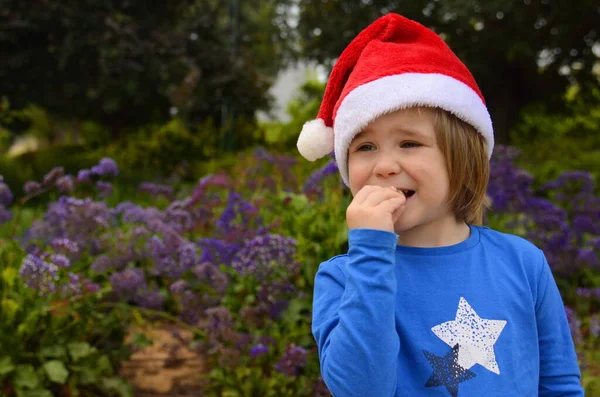 Mały Chłopiec Kwitnącym Ogrodzie Kapeluszu Świętego Mikołaja Koncepcja Boże Narodzenie — Zdjęcie stockowe