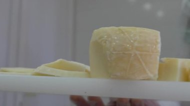 Beyaz önlüklü ve eldivenli bir kadın halloumi peyniri keser. Yakın çekim, yavaş çekim 4K. Çiftlikte peynir tatma. El yapımı, ev yapımı Yunan peyniri..
