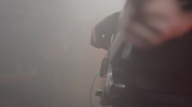 Adam kulübün sahnesinde bas gitar çalıyor. Bas gitaristin parmakları yakın, yavaş çekim 4k