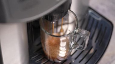 Kahve makinesi Americano kahvesi doldurur. Kremalı kahve. Yakın çekim, ağır çekim 4 km şeffaf büyük kupa.