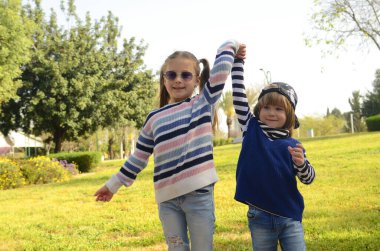 6 yaşında bir kız ve 4 yaşında bir oğlan, neşeli arkadaşlar. Kavram: abla, ilk aşk. Çocuklar parkta oynuyor. Kız küçük erkek kardeşine bakıyor..