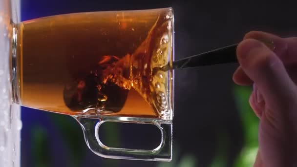 お茶のグラスカップ 黒ティーバッグはお湯に溶解します 沸騰した水から蒸気 透明なガラスだ 朝のお茶 垂直ビデオスローモーション4K — ストック動画