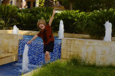 Bir anaokulu çocuğu çeşmede suyla oynar. Yaz, tatiller, ailenle seyahat.