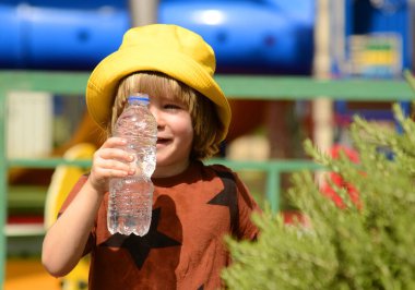 Tatlı bir çocuk plastik şişeden su içer. Yaz susuzluğu, anaokulu öğrencisi sıcak bir günde su içiyor.