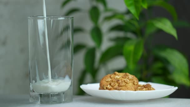 ミルクは オートミールクッキーとガラス 朝の朝食ミルクに注がれます スローモーション — ストック動画