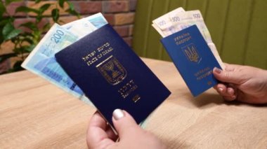 Bir İsrail vatandaşının pasaportu ve bir Ukrayna vatandaşının pasaportu, ülkene dönüş, aliyah. Kağıt para, yeni İsrail şekeli ve Hryvnia. Emme sepeti. Dönüş Yasası 'na göre yardım.