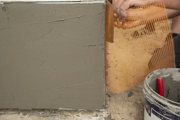 一个建筑承包商正在安装一个加固网 以隔离房屋的外墙 — 图库照片