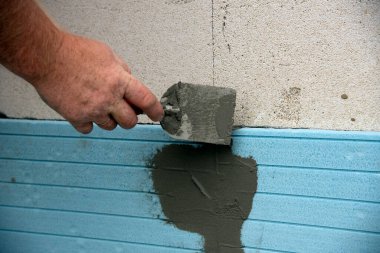 The installation of insulation extruded polystyrene panels . Worker is installing Extruded polystyrene panels. The worker with a spatula and glue removes the cracks between extruded polystyrene panels clipart