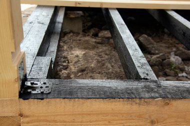 Terasın ahşap çerçevesine bituminöz astar takıyorum. Ahşap parmaklıklar ve tahtalar su geçirmez. Su geçirmez tahta. Bağlamak için metal köşe.