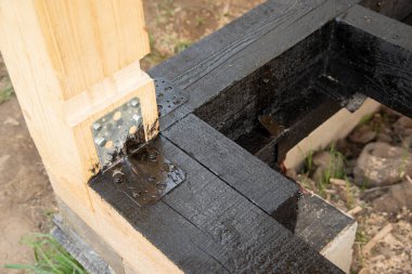 Terasın ahşap çerçevesine bituminöz astar takıyorum. Ahşap parmaklıklar ve tahtalar su geçirmez. Su geçirmez tahta. Bağlamak için metal köşe.