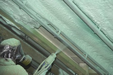 Sprey köpük yalıtımı kuruluyor. İşçi duvarlara köpük yalıtımı yapıyor..