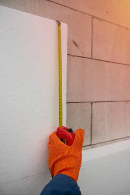 Şerit metresi olan bir müteahhit, köpük tabakasını ölçer. Evi ısıtma süreci..