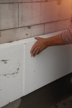 Bir müteahhit polistiren köpük çarşaf takar. Evin duvarlarının termal izolasyon süreci.