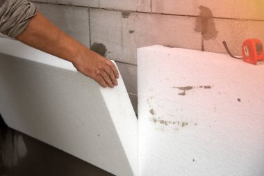 Bir müteahhit polistiren köpük çarşaf takar. Evin duvarlarının termal izolasyon süreci. Termal yalıtım.