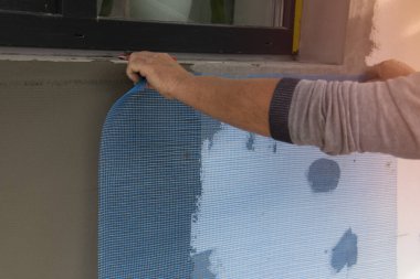 Fiberglas ağ takviye ızgarası kurma işlemi. İşçi fiberglas ağ kuruyor.