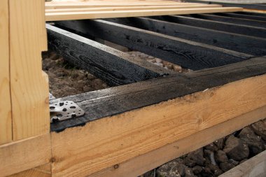 Terasın ahşap çerçevesine bituminöz astar takıyorum. Ahşap parmaklıklar ve tahtalar su geçirmez. Su geçirmez tahta. Bağlamak için metal köşe.