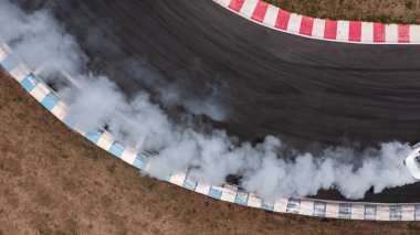 Havadan görünüşlü beyaz araba hız yolunda yanan lastiklerden gelen dumanla sürükleniyor, hız yolunda sürüklenen araba, spor araba tekerleği sürükleniyor ve sigara içiyor..