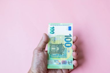 Pembe arka planda Avro banknotları tutan eller, Avro banknotları, Pembe arka planda 100 Euro, Pembe arka planda banknotlar yığını,.