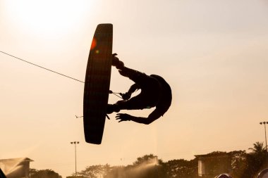 Siluet Wakeboard 'cu gün batımında numaralar yapıyor, genç sörfçü kablo parkında wakeboard yapıyor, ekstrem sporcu wakeboard yaparken eğleniyor..