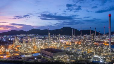 Geceleri petrol rafinerisi arka planına sahip hava manzaralı petrol ve gaz tankı, gece petrokimya fabrikasının parıltılı ışıklandırması, petrol üretimi, petrokimya fabrikasında ürün tankı.