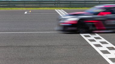 Race car blurred motion crossing the finish line on international circuit speed track, Motion blur Racing car crossing finish line on asphalt race track. clipart