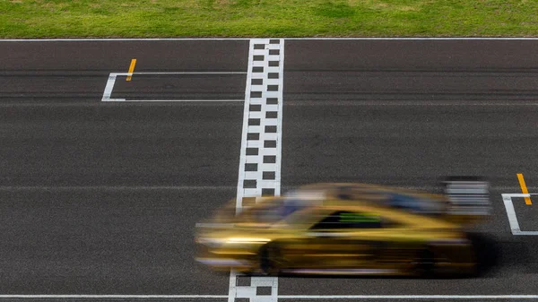 赛车在国际赛道上越过终点线的模糊运动 在沥青路面赛道上穿越终点线的模糊运动 图库图片
