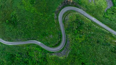 Dağ yolundaki yeşil ormandan geçen hava manzaralı yol yeşil ormandan geçen asfalt yolda giden araba yukarıdan geçen kıvrımlı yol..